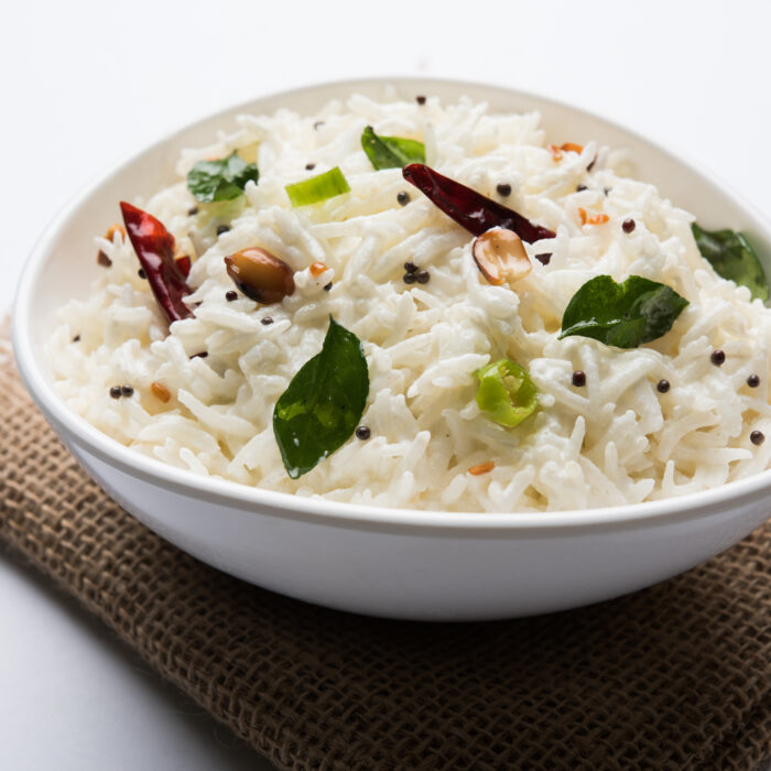 Curd Rice or Dahi Bhat OR Chawal with curry leaf, peanuts and chilli- Served in a bowl over moody background. Selective focus