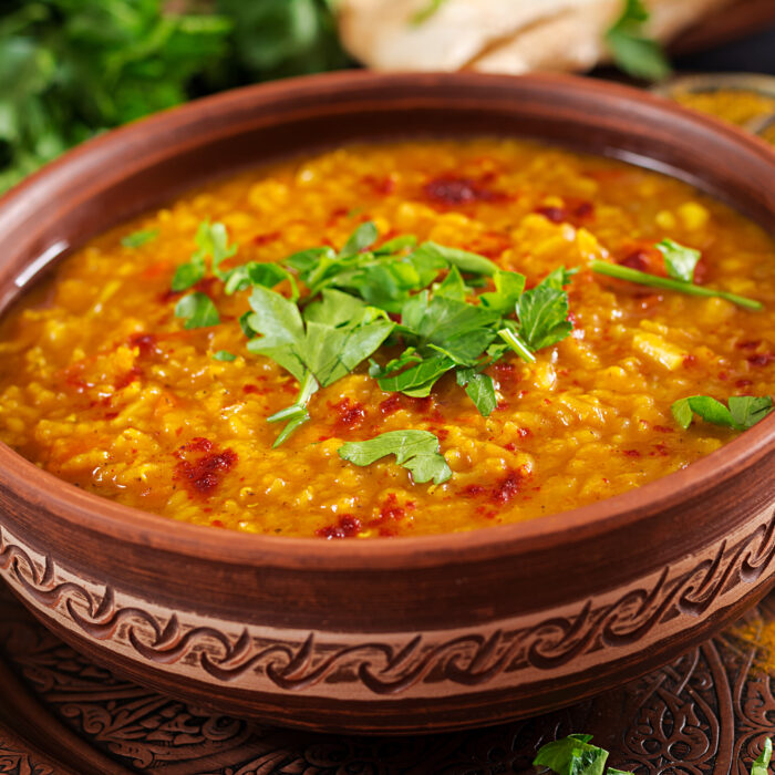 Indian dal. Traditional Indian soup lentils.  Indian Dhal spicy curry in bowl, spices, herbs, rustic black wooden background. Authentic Indian dish. Overhead