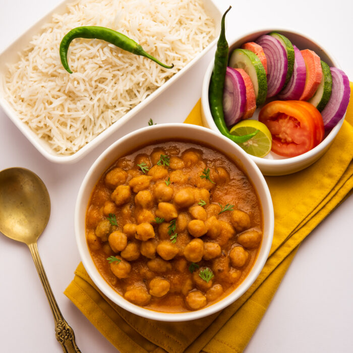 Indian food chole chawal or spicy Chickpea curry with plain rice served with green salad. selective focus