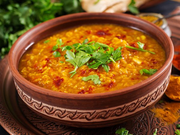 Indian dal. Traditional Indian soup lentils.  Indian Dhal spicy curry in bowl, spices, herbs, rustic black wooden background. Authentic Indian dish. Overhead